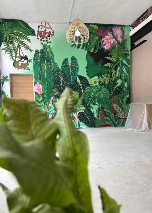 Mural interior de temática tropical en Torrelavega con gran pared vegetal y lámpara decorativa