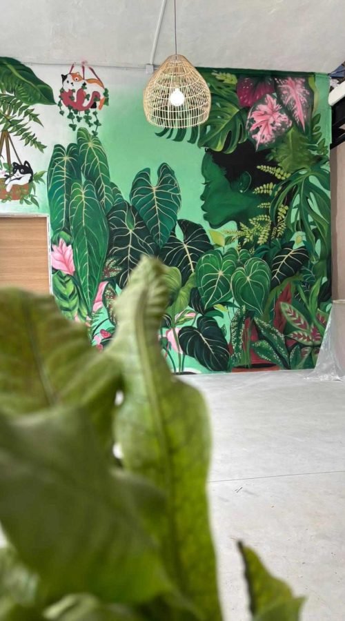 Mural interior de temática tropical en Torrelavega con gran pared vegetal y lámpara decorativa