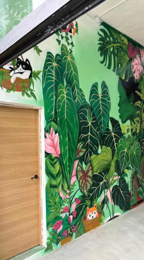 Mural de naturaleza en interior comercial de Cantabria con pared botánica y retrato femenino verde