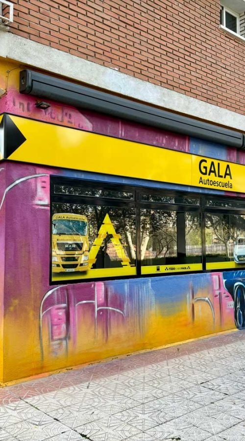 Mural con coches y motos en fachada de Autoescuelas Gala en Móstoles