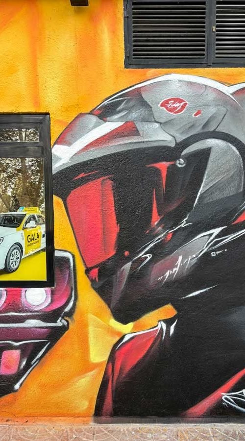 Mural con coches y motos en fachada de Autoescuelas Gala en Móstoles