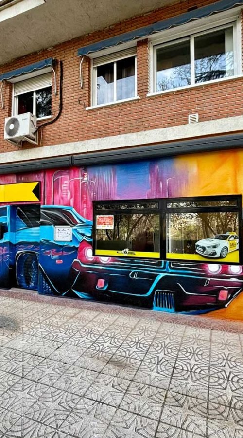 Mural con coches y motos en fachada de Autoescuelas Gala en Móstoles