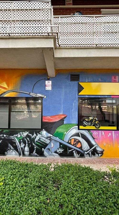 Mural con coches y motos en fachada de Autoescuelas Gala en Móstoles