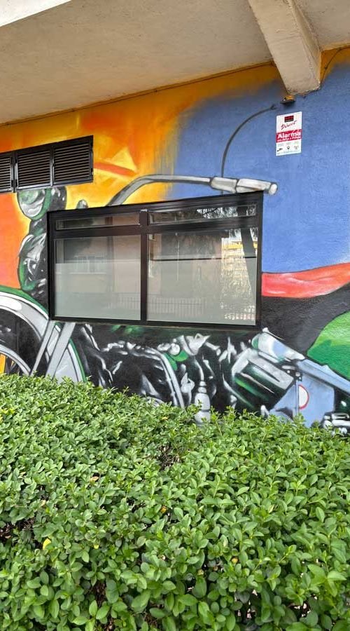Mural con coches y motos en fachada de Autoescuelas Gala en Móstoles