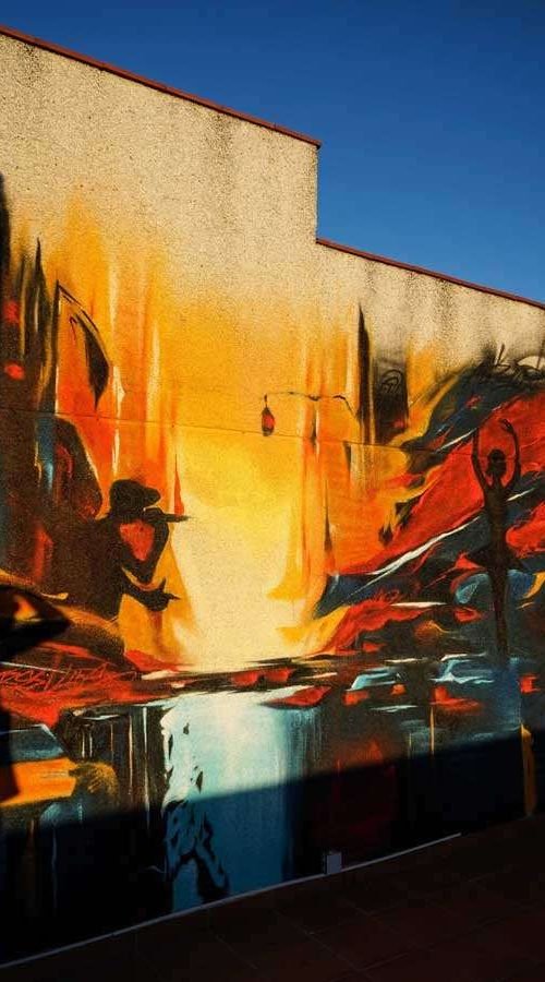 Mural artístico en terraza privada con siluetas y paisajes cálidos