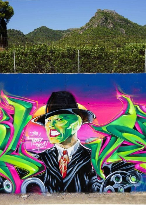 Mural de La Máscara estilo graffiti con fondo rosa y verde
