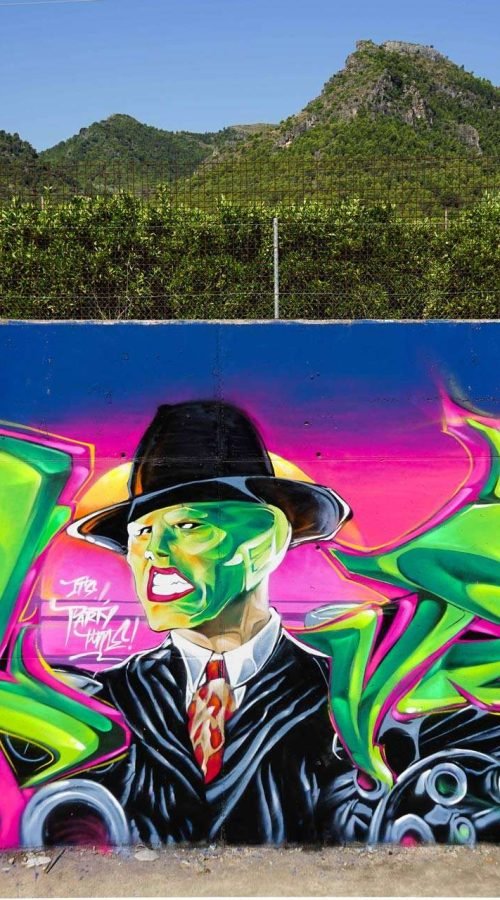 Mural de La Máscara estilo graffiti con fondo rosa y verde