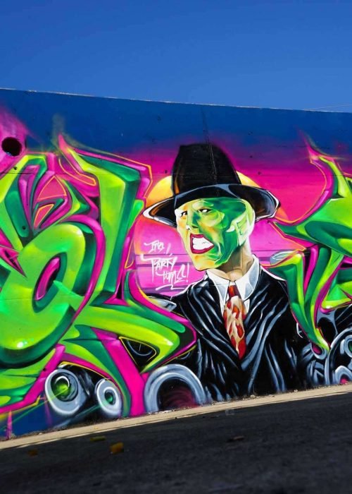 Mural de La Máscara estilo graffiti con fondo rosa y verde