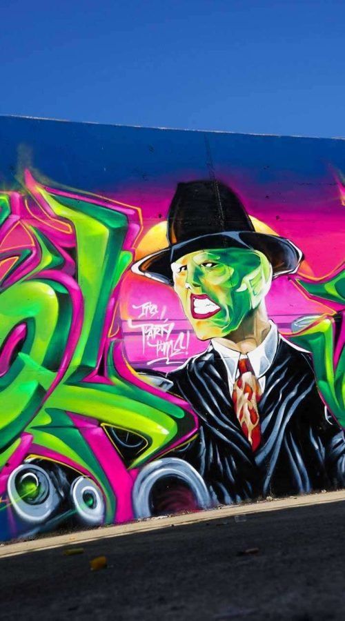 Mural de La Máscara estilo graffiti con fondo rosa y verde