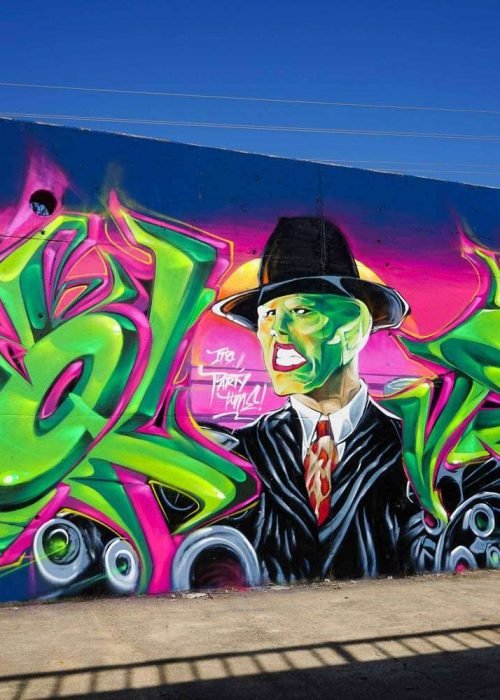 Mural de La Máscara estilo graffiti con fondo rosa y verde