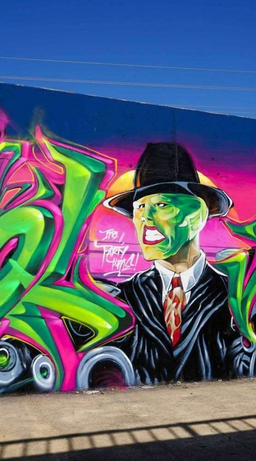 Mural de La Máscara estilo graffiti con fondo rosa y verde