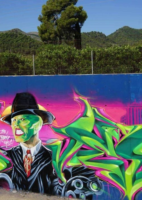 Mural de La Máscara estilo graffiti con fondo rosa y verde