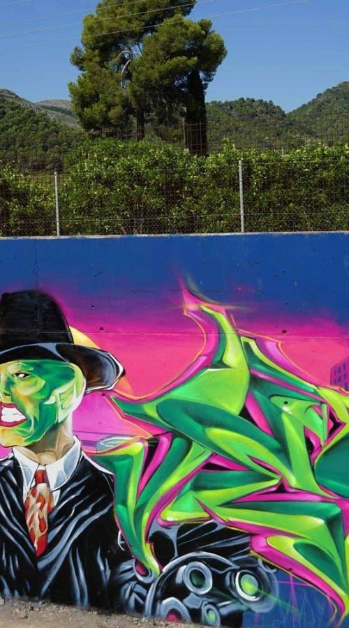 Mural de La Máscara estilo graffiti con fondo rosa y verde