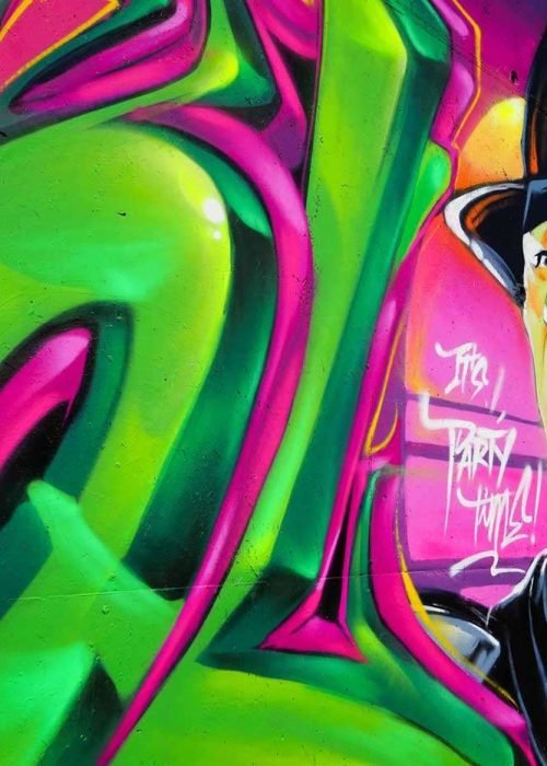 Mural de La Máscara estilo graffiti con fondo rosa y verde