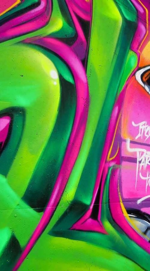 Mural de La Máscara estilo graffiti con fondo rosa y verde