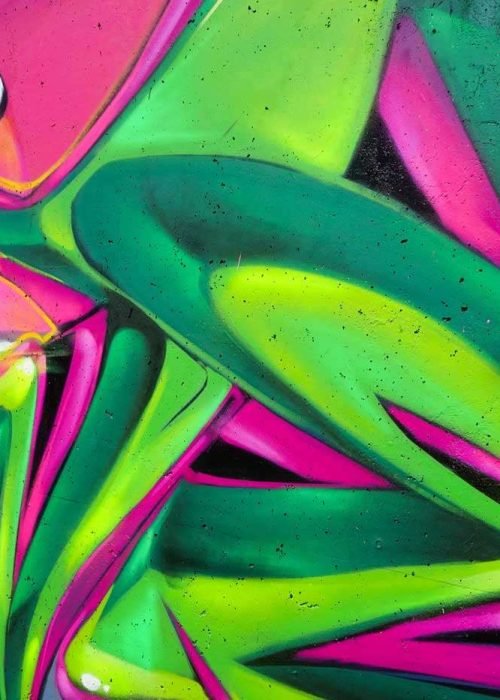 Mural de La Máscara estilo graffiti con fondo rosa y verde