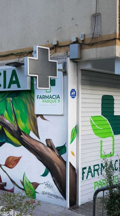 Mural con ramas y hojas en fachada de Farmacia Parque9, graffiti para imagen de salud